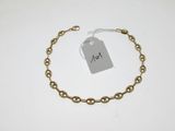 a close up of a gold chain bracelet with a tag on it