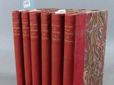 six livres rouges sont empilés les uns sur les autres sur une surface grise