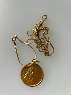 collier composé d'une pièce d'or posée sur un fond blanc et entourée d'une chaîne
