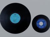 two black vinyl records sitting on top of a white surface