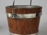 a wooden bucket with a metal handle on a white surface