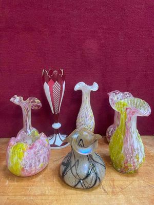 plusieurs vases en verre posés sur une table en bois, sur fond rouge