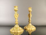 pair of gold candlesticks on a black table with a gray background