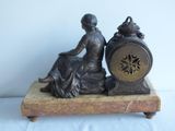 a statue of a woman sitting on a table with a clock