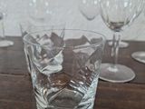 a glass of water sitting on a table next to several empty wine glasses