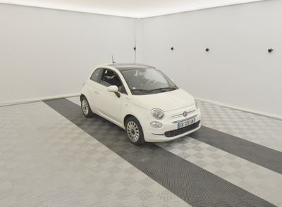une petite voiture blanche garée dans une pièce dont le sol est en damier noir et blanc