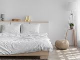 un lit avec des draps blancs et des oreillers, dans une chambre blanche