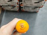 a person holding an orange in front of a stack of boxes