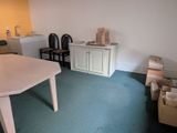 a room with a table, chairs, and a refrigerator in it