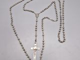 un collier de chapelet avec une croix suspendue à une chaîne, posé sur une table