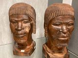 two wooden head sculptures on display in a glass case