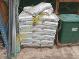 a pile of bags of cement next to a green trash can