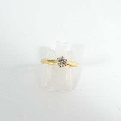 gros plan d'une bague en or surmontée d'un diamant