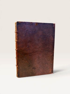an old book sitting on top of a white table next to a white wall