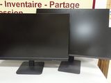 two computer monitors sitting on top of a table in front of a sign