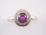 gros plan d'une bague avec une pierre violette entourée de diamants