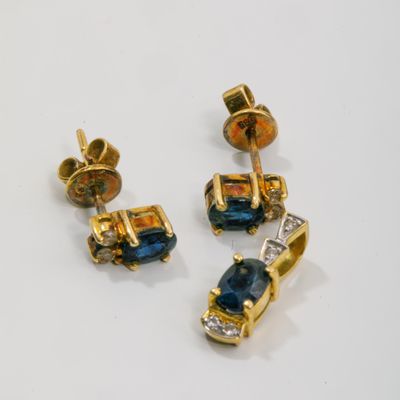 deux paires de boucles d'oreilles en or et saphir posées sur un fond blanc