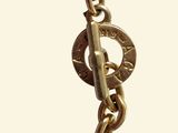 a close up of a gold chain with a coin on it