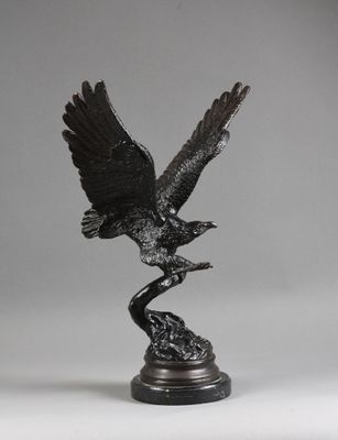 une statue en bronze représentant un oiseau perché sur une branche, les ailes déployées