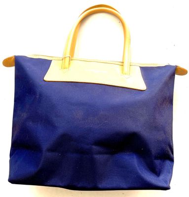 a blue bag with a tan handle hanging on a wall