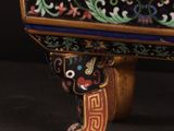 an ornately decorated chest on a wooden stand with a black background