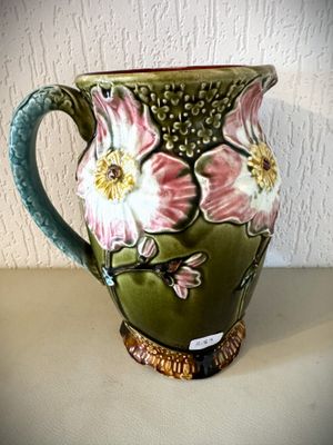 un vase vert orné de fleurs roses, posé sur une table