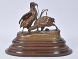 bronze sculpture of two birds on a wooden base on a white background
