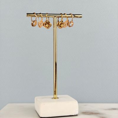 un gros plan d'un présentoir à bijoux en or posé sur une surface en marbre