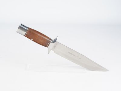 un couteau avec un manche en bois sur une surface blanche