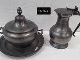 un pichet en argent et une assiette en argent posés sur une table blanche
