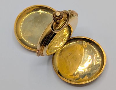 an image of a gold pocket watch sitting on top of a white surface