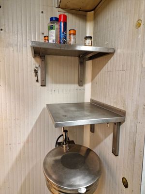 un évier en métal dans un coin d'une petite pièce