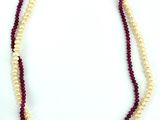 deux rangs de perles rouges et blanches, avec un fermoir doré, sur fond blanc