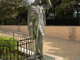 a statue of a man holding a hat on a pedestal