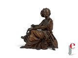 bronze statue of a woman sitting on a chair with a bird in her hand
