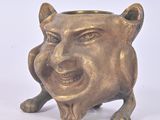 a small bronze statue of a smiling cat on a white surface