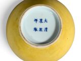 a yellow vase with blue writing on it on a white surface