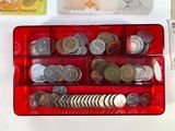 a red box filled with coins and money next to a toothbrush