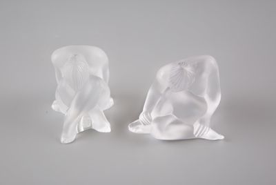 deux sculptures représentant un homme et une femme assis sur une surface blanche