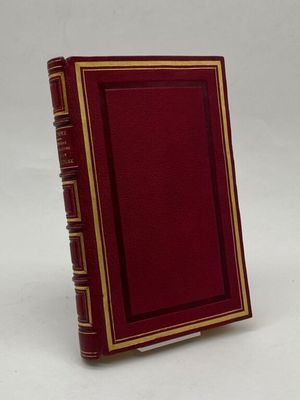 an old red book with gold trim sitting on top of a white surface