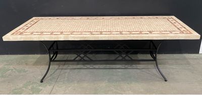 un gros plan d'une table avec un plateau en carrelage et des pieds en fer