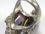 silver ring with amethorate and gold accents sitting on a white surface