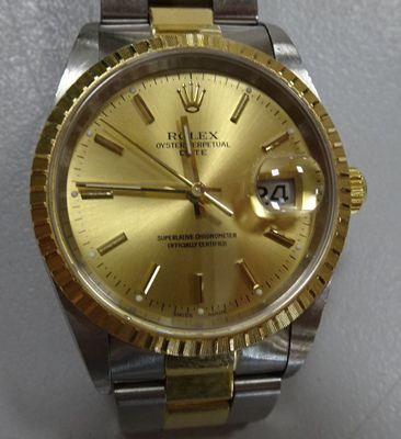 a watch with a gold dial on a silver and gold bracelet