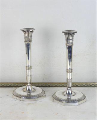 deux bougeoirs en argent posés sur une table en marbre
