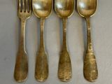 six spoons and a fork are arranged on a table