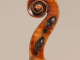 an antique violin with a scroll and a bow on a stand