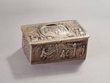 an old silver box with a scene on it sitting on a table