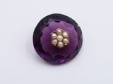 a purple flower with pearls in it on a white surface