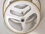 a close up of a white and gold wheel on a white wall