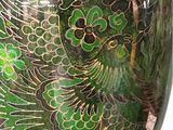 a green vase with a bird on it on a stand